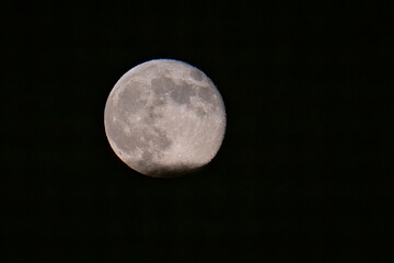 Full moon rising above a layer of cloud
