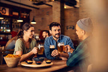 Young happy friends talk while drinking beer in pub.
