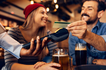 Close up of man using credit card while paying in bar.