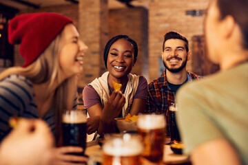 Happy black woman and her friends talk and have fun in bar.