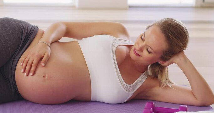 Baby enjoyed that one. 4k video footage of a pregnant woman relaxing on her yoga mat after a workout.