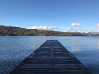 Lake view with a wooden jetty and a blue sky background. Lake Windermere England. 