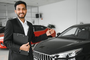 indian cheerful car salesman at showroom.
