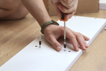 Man's Hand Using Screw Driver Assembling Wooden Furniture