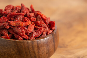 A Bowl of Red Dehydrated Goji Berries in a Wooden Bowl in the Kitchen