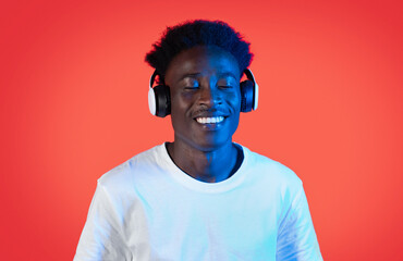 Joyful black guy hipster listening to music with closed eyes