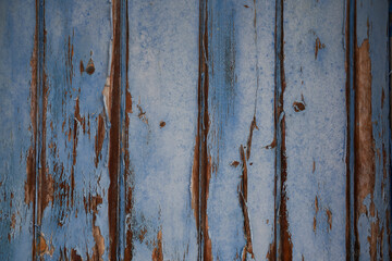 Peeling blue painted wooden old door background. Old weathered locker room fence from an abandoned...