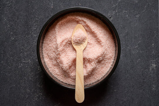 Himalayan pink salt in a black bowl with wooden spoon - Powered by Adobe