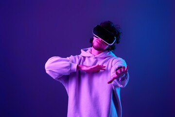 man in vr glasses and sweatshirt plays on blue background.