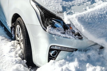 A car under the snow after a blizzard on a sunny day. The car is in the snow. A snow-covered car in a winter storm.