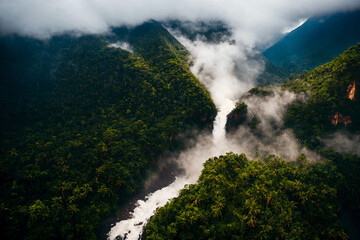 Aerial view of a tropical rainforest mountain valley with a gient waterfall and a wild river. Generative AI