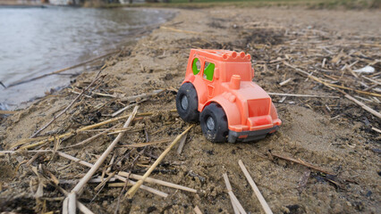 A plastic children's toy truck abandoned on a lakeside beach
