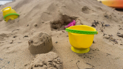 Fototapeta na wymiar abandoned yellow bucket children's toy lying in the sand