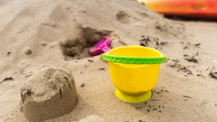 Fototapeta na wymiar abandoned yellow bucket children's toy lying in the sand