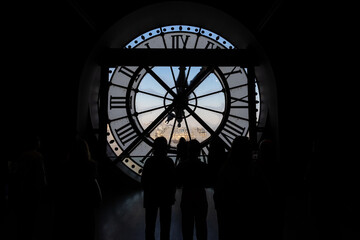 Unrecognizable people have a view of the city of Paris through a clock with a window
