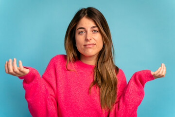 Young woman in sweater pointing at camera in studio