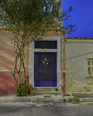 A Christmas decorated vintage house door by the sidewalk. Night walk in Athens, Greece.