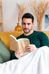 Young man with book sitting on sofa