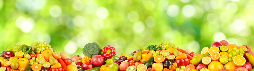 Large collection of fresh fruits, vegetables and berries on green background.