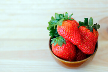 fresh strawberries in a  ceramic bowl on wooden background with space for text, healthy strawberry fruits, summer fruit