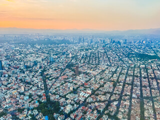 Aerial photography of Mexico City, houses, buildings and its large avenues are distinguished at sunset.