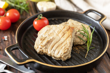 Restaurant food. Seafood. Rustic style. Cooked juicy tuna steak  with spices, tomatoes and rosemary on a stone plate.