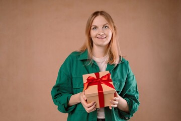 Young smiling happy pretty woman holding present box celebrating birthday, posing on background. 