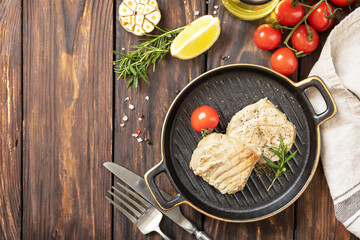 Restaurant food. Seafood. Rustic style. Cooked juicy tuna steak  with spices, tomatoes and rosemary on a stone plate. View from above.