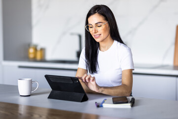 Young pretty woman using a tablet computer to cook in her kitchen .