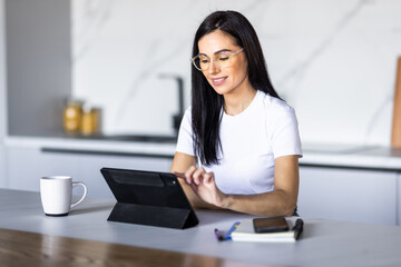 Fototapeta premium Young pretty woman using a tablet computer to cook in her kitchen .