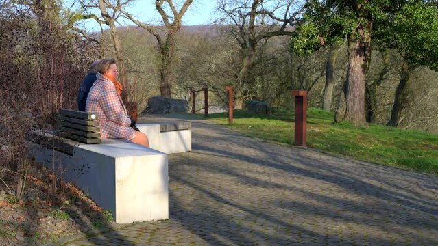 Senior couple sitting on a park bench together on a clear but cold winter day
