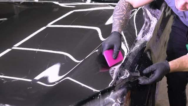 Man covering car with vinyl polyurethane tape. Films for the car. Sticker protective film on the car