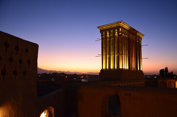 illuminated wind tower in Yazd in evening light with sunset in background