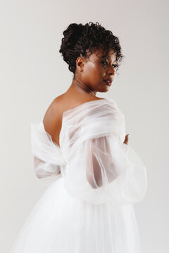 Model with dark skin in a white dress. Wedding make-up, wedding hairstyle.