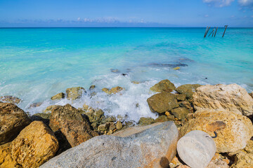 Fototapeta na wymiar Beautiful view of coastline of beach barred with large stones for cutting waves of Atlantic Ocean. Aruba.