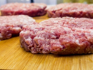 Meat cheese burgers for hamburger lie on a wooden board.