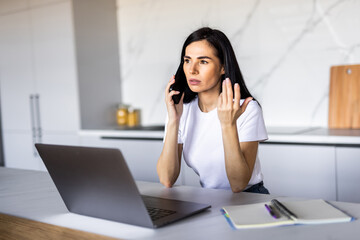 Beautiful young woman calling bank using cell phone concerning information on credit card that she is holding. Serious female connecting to mobile banking service using electronic device