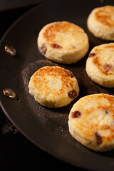 Delicious Ukrainian syrniki being cooked in a kitchen. Sweet cheese cakes frying on hot pan. Traditinal dessert food from Ukraine