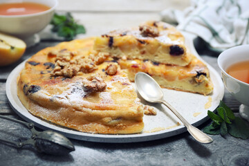 French cuisine. Matefaim. Sweet Apple Pancake with dried cranberries and walnuts, two cups of tea for breakfast