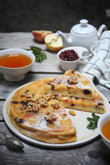 French cuisine. Matefaim. Sweet Apple Pancake with dried cranberries and walnuts, two cups of tea for breakfast