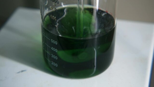 Chemical process. Stock footage. A small test tube with a green chemical solution that is mixed.