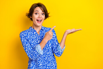 Photo of astonished adorable lady blue stylish clothes arm direct empty space quality product offer isolated on yellow color background