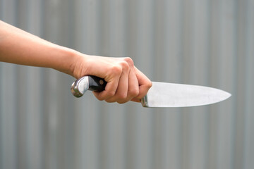 sharp dangerous knife in a female hand on a gray background. Self defense, fear, horror, murder