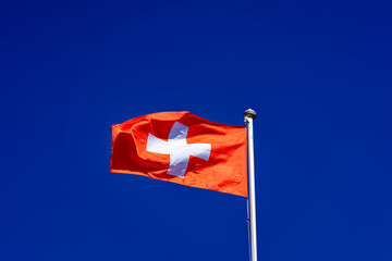 Fototapeta na wymiar Swiss flag waving at local mountain Gütsch, Canton Luzern, on a sunny spring day. Photo taken March 22nd, 2023, Lucerne, Switzerland.