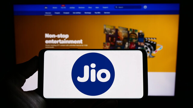 Stuttgart, Germany - 03-18-2023: Person holding cellphone with logo of Indian telecommunications company Reliance Jio on screen in front of webpage. Focus on phone display.