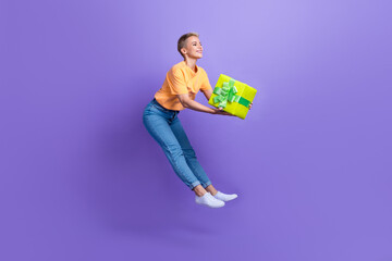 Full length photo of carefree active person jumping arms hold desirable giftbox isolated on violet color background
