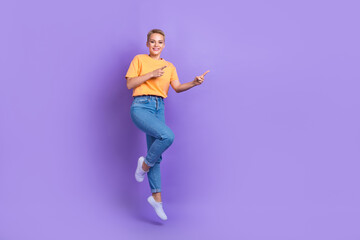 Fototapeta na wymiar Full length photo of positive nice girl dressed white sneakers jeans pants directing empty space isolated on violet color background