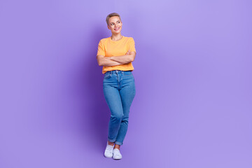 Fototapeta na wymiar Full length photo of cheerful positive girl dressed jeans white sneakers arms folded look empty space isolated on violet color background