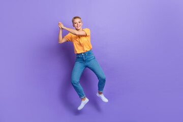 Fototapeta na wymiar Full length photo of friendly playful girl dressed jeans white sneakers hold imaginary tennis racket isolated on violet color background