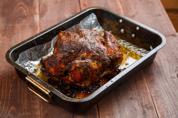 Baked whole chicken in spices golden brown on a baking sheet.